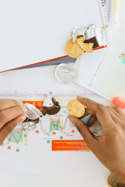 Close-up of hands peeling chocolate coins over financial graphs, symbolizing finance and investment.